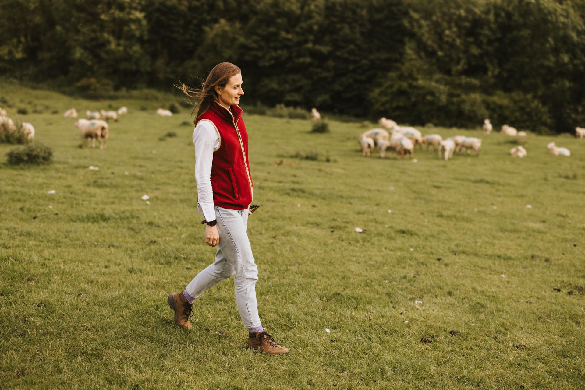 Natalie walking in a field of sheep